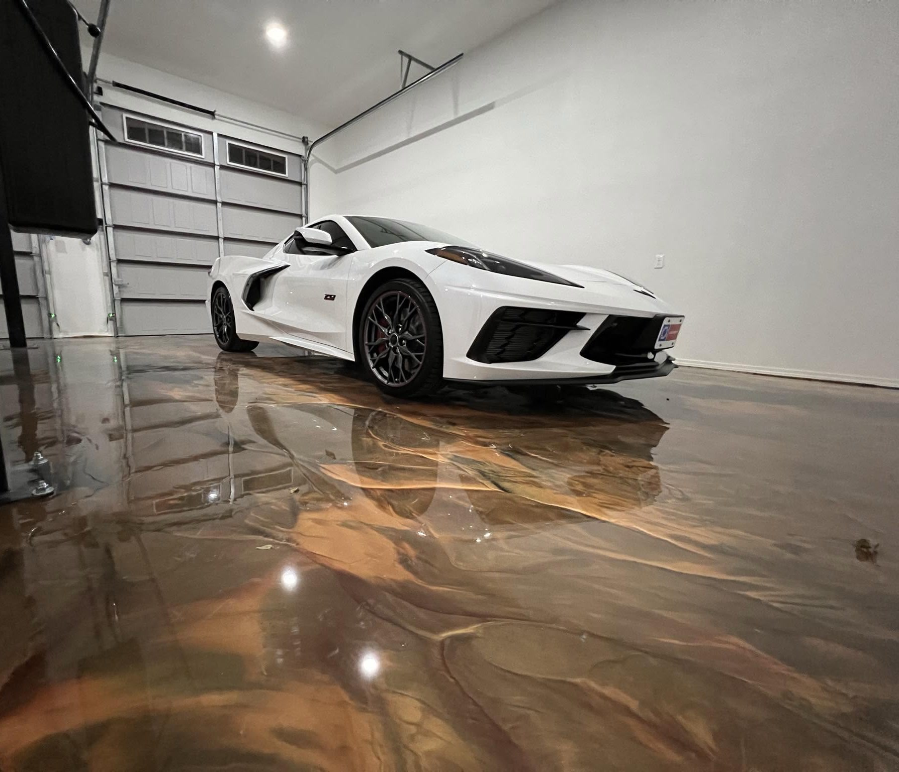 White Corvette with a flawless, swirl-free finish after paint correction, reflected in a glossy garage floor, by I Auto Detailing in McAllen, TX